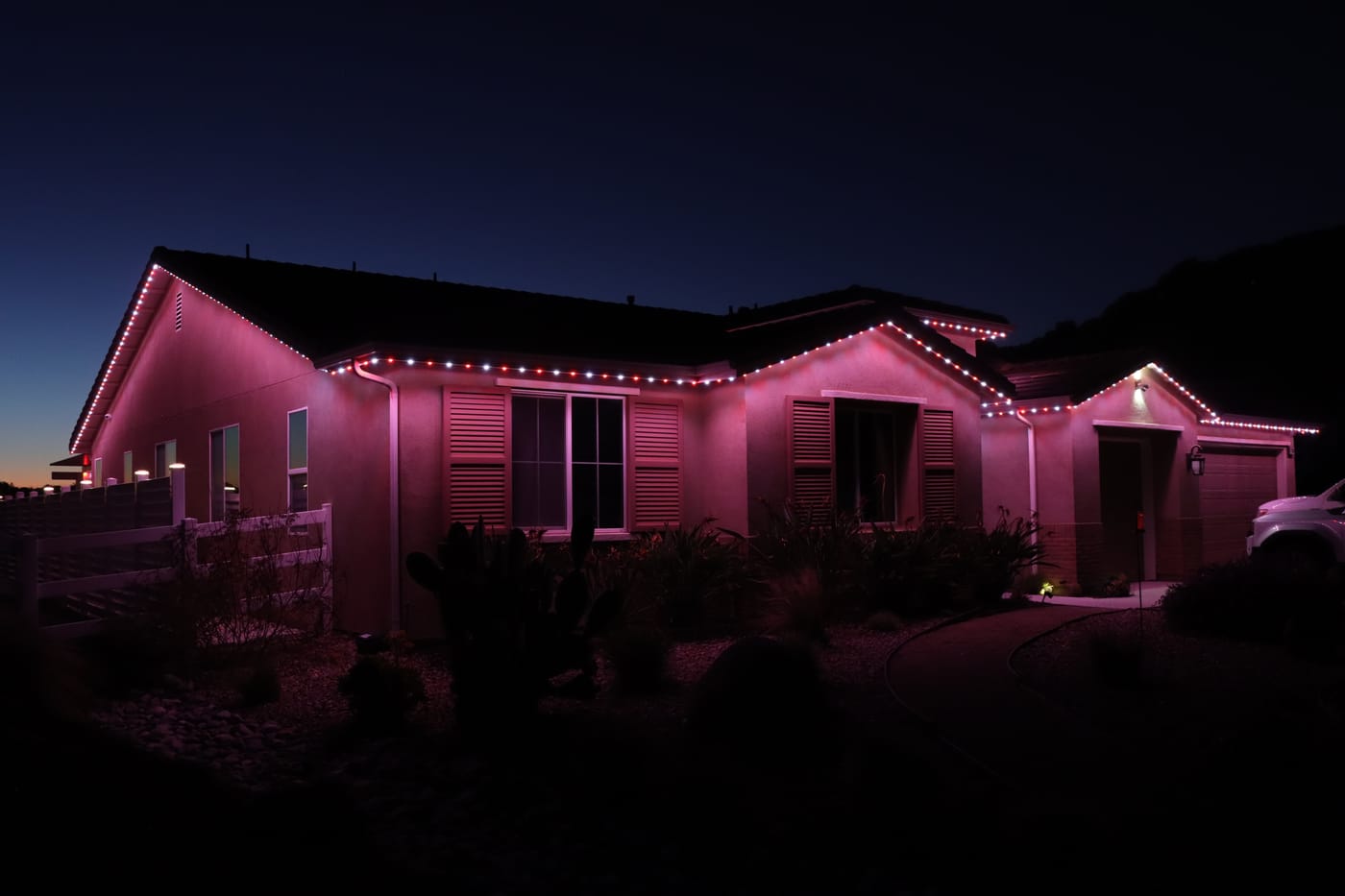 Home with colorful permanent exterior roofline lighting at dusk